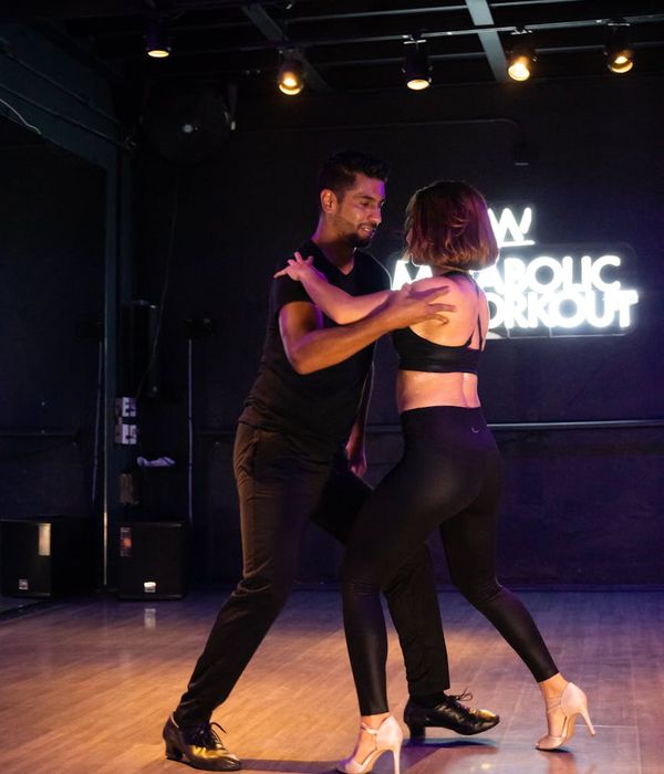 Energetic woman practicing dynamic movements in a dark studio atmosphere.
